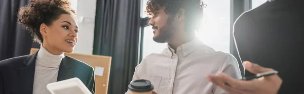Positivo interrazziale uomini d'affari con tablet digitale e caffè parlando in ufficio, banner — Foto stock