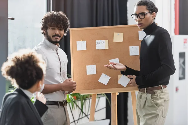 Multiethnic businessmen talking to african american colleague near board in office — Stock Photo