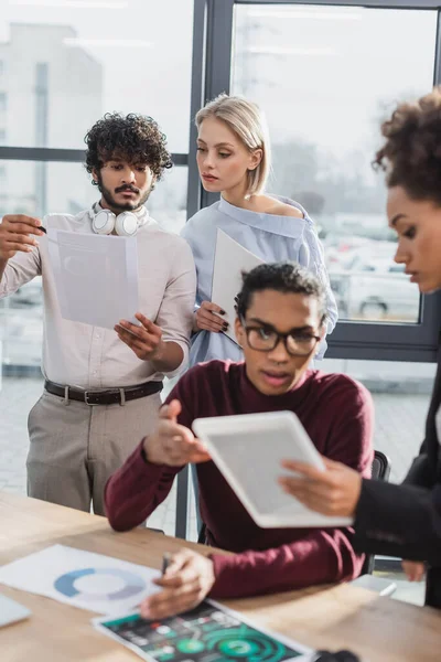 Indian businessman holding document near colleague in office — Stock Photo