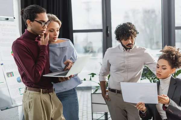 Imprenditori multiculturali che lavorano con carta e laptop in ufficio — Foto stock