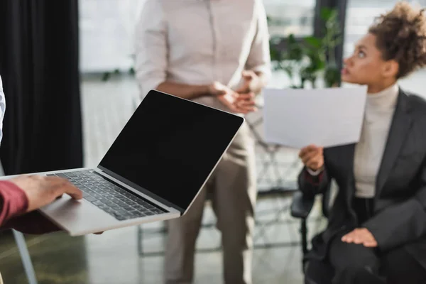 Hombre de negocios afroamericano sosteniendo portátil con pantalla en blanco en la oficina — Stock Photo