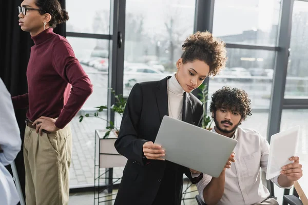 Uomini d'affari multietnici che utilizzano dispositivi vicino ai colleghi in carica — Foto stock