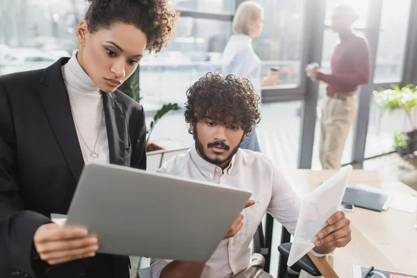 Des hommes d'affaires multiethniques utilisant un ordinateur portable et une tablette numérique au bureau — Photo de stock