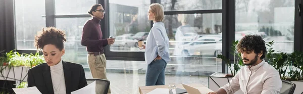 Des hommes d'affaires multiethniques travaillant près de collègues flous au bureau, bannière — Photo de stock