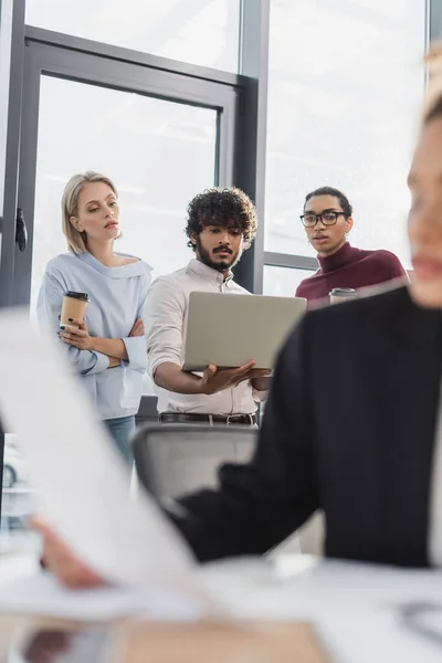 Multicultural business people with coffee using laptop in office — Stock Photo