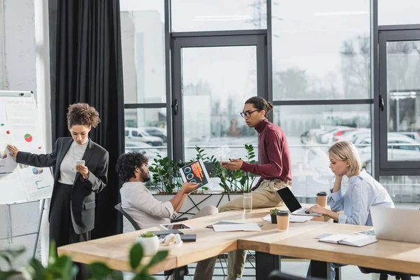 Uomini d'affari multietnici che lavorano con documenti e dispositivi in ufficio — Foto stock