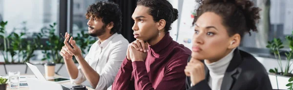 Gente de negocios interracial reflexiva mirando hacia otro lado en la oficina, pancarta - foto de stock