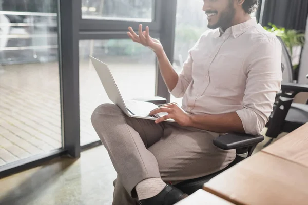 Розбитий погляд бізнесмена, який посміхається під час відеодзвінків на ноутбуці в офісі — стокове фото