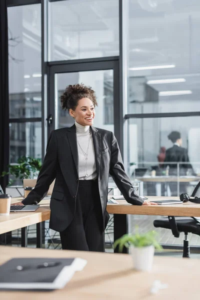 Young african american businesswoman smiling near working table in office — Stock Photo