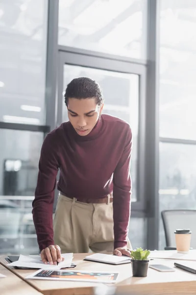 Young african american businessman working with papers near notebook in office — Stock Photo