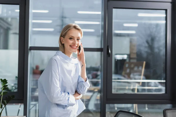 Young businesswoman talking on smartphone in office — Stock Photo