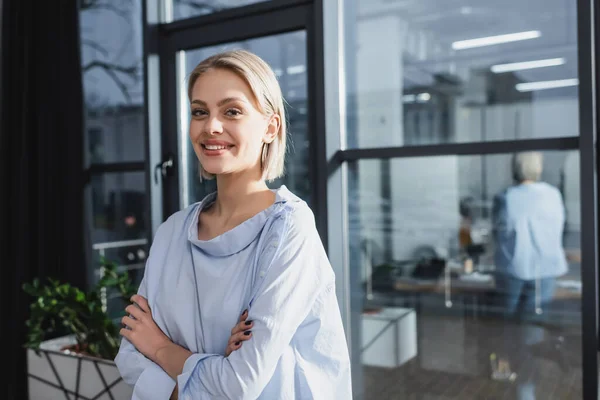 Femme d'affaires positive croisant les bras au bureau — Photo de stock