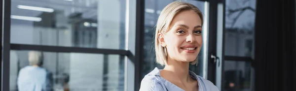 Mujer de negocios positiva mirando a la cámara en la oficina, pancarta - foto de stock