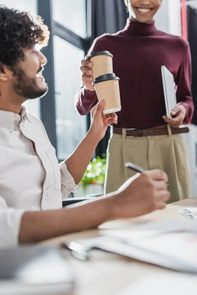 Des hommes d'affaires multiethniques tenant un café à emporter pendant qu'ils travaillent au bureau — Photo de stock