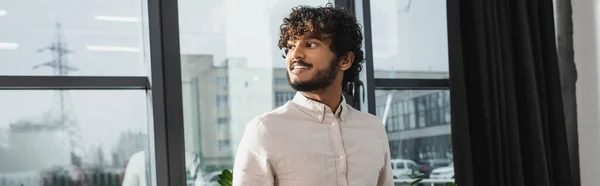 Alegre empresario indio mirando hacia otro lado en la oficina, pancarta - foto de stock