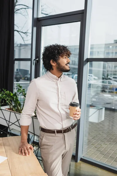 Vista laterale di uomo d'affari indiano positivo che tiene il caffè per andare in ufficio — Foto stock