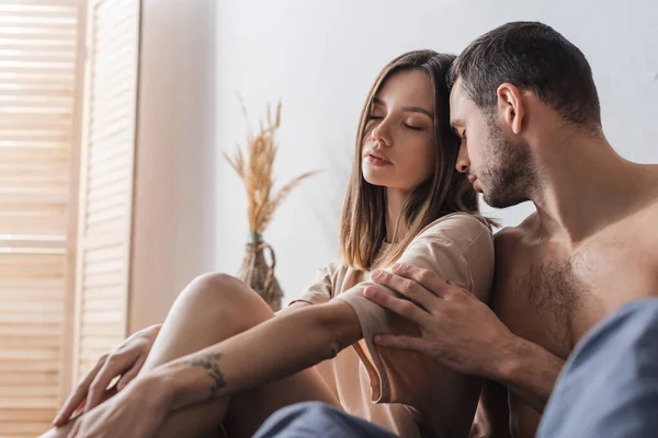 Сексуальний чоловік торкається дівчини в футболці на ліжку вдома — стокове фото
