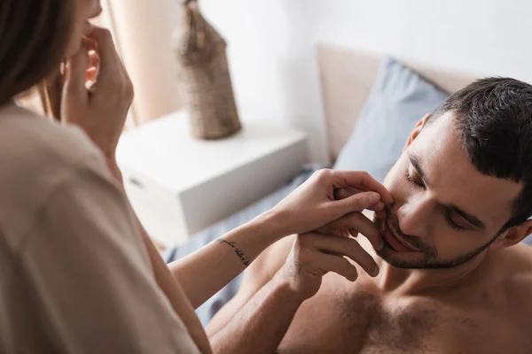 Blurred young woman touching sexy man on bed at home — Stock Photo