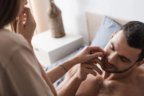 Blurred joven mujer tocando sexy hombre en la cama en casa - foto de stock