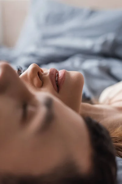 Jovem deitada perto de namorado borrado na cama em casa — Fotografia de Stock
