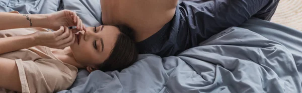 Jeune femme en t-shirt couché près du copain torse nu sur le lit, bannière — Photo de stock