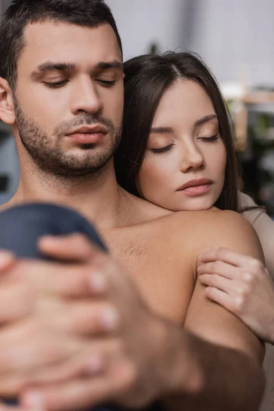 Mujer joven abrazando novio sin camisa en casa - foto de stock