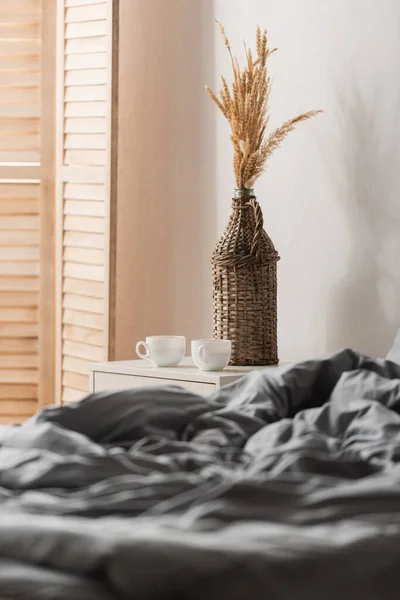 Cups of coffee on bedside table near bed at home — Stock Photo
