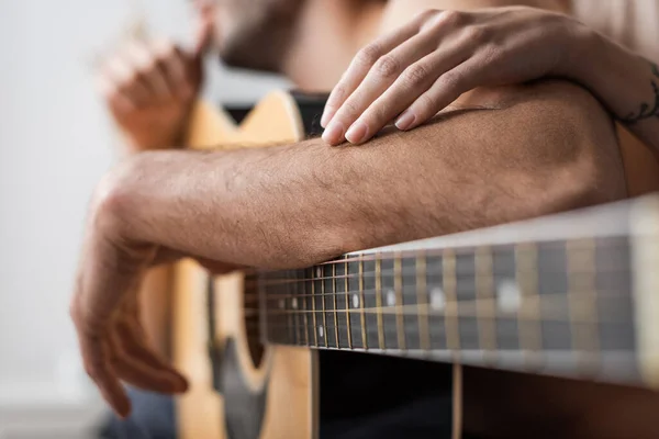 Vista recortada de la mujer tocando brazo de novio cerca de la guitarra acústica - foto de stock