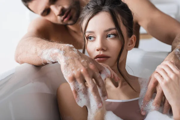 Young woman touching hands of blurred shirtless boyfriend at home — Stock Photo