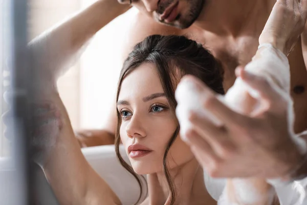 Homme torse nu touchant petite amie en mousse dans la baignoire à la maison — Photo de stock