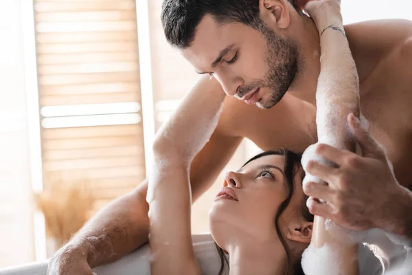 Bärtiger Mann berührt Freundin in Badewanne mit Schaum — Stockfoto