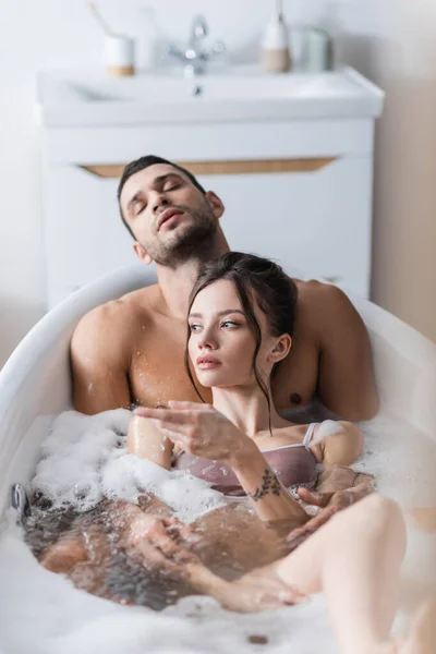 Woman pointing with finger while taking bath with sexy boyfriend at home — Stock Photo