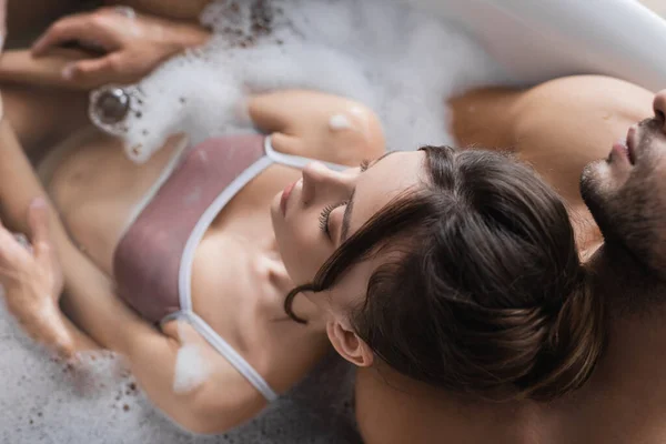 Vue aérienne du couple sexy prenant un bain flou avec de la mousse à la maison — Photo de stock