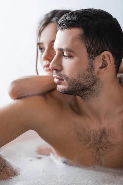 Barbudo hombre tomando baño con borrosa novia en casa - foto de stock