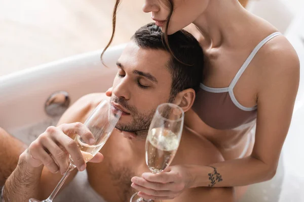 Blick aus der Vogelperspektive: Junger Mann trinkt Champagner in Badewanne in der Nähe seiner Freundin — Stockfoto