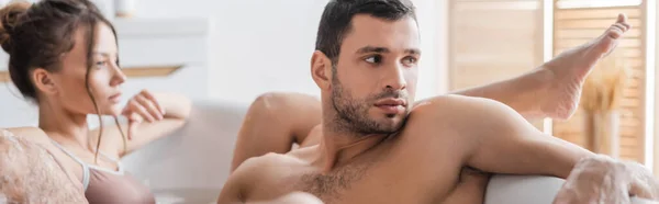 Young man taking bath with blurred girlfriend at home, banner — Stock Photo