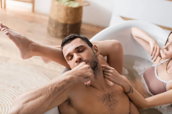 Розмита жінка торкається шиї м'язового хлопця у ванній — стокове фото