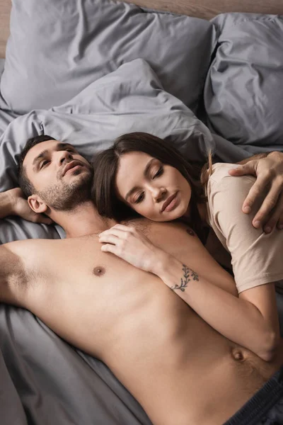 Visão de alto ângulo de homem muscular abraçando namorada na cama — Fotografia de Stock