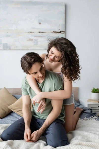 Mujer contenta y rizada abrazando novio en el dormitorio - foto de stock