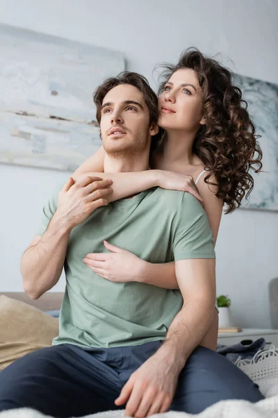 Femme bouclée étreignant petit ami et regardant loin dans la chambre — Photo de stock