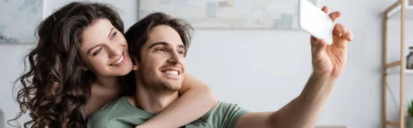 Happy young couple taking selfie at home, banner — Stock Photo