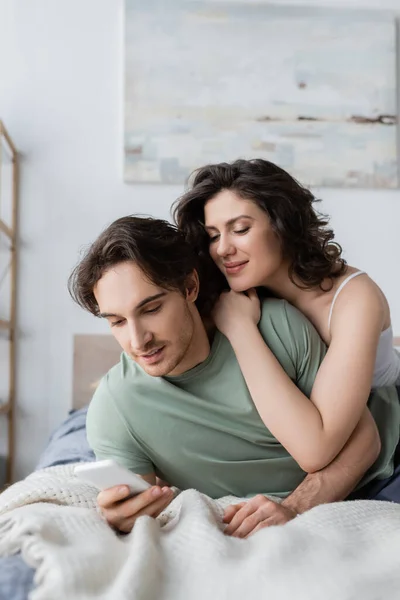 Young man and woman looking at smartphone at home — Stock Photo