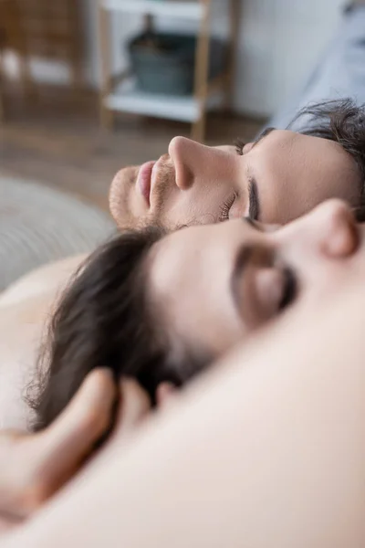 Vue rapprochée de jeune homme avec les yeux fermés couché près de petite amie floue — Photo de stock