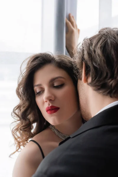 Homme en costume séduire jeune femme bouclée avec des lèvres rouges — Photo de stock