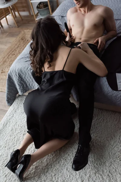 Back view of curly woman in black slip dress undressing man in pants — Stock Photo