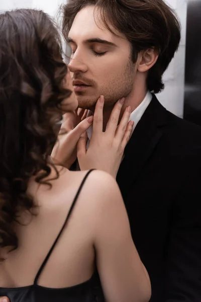 Curly young woman kissing man in blazer — Stock Photo