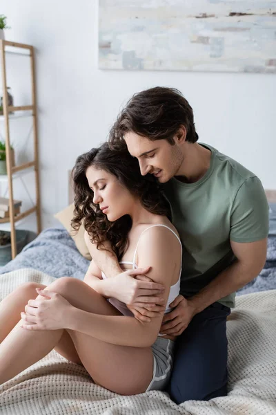 Homem alegre em verde t-shirt abraçando mulher sensual em casa — Fotografia de Stock