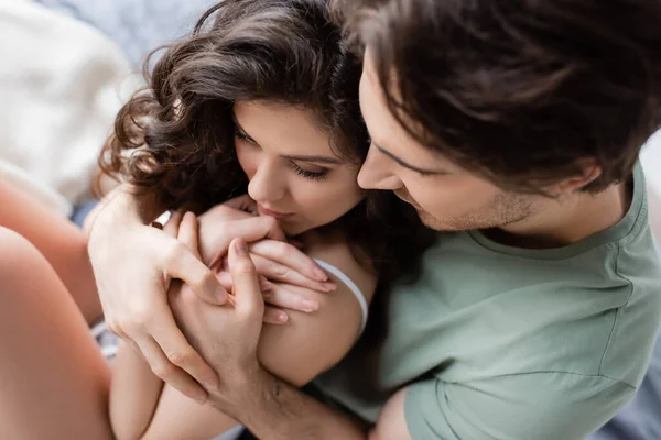 Vista de ángulo alto del hombre en camiseta verde abrazando a la mujer sensual - foto de stock