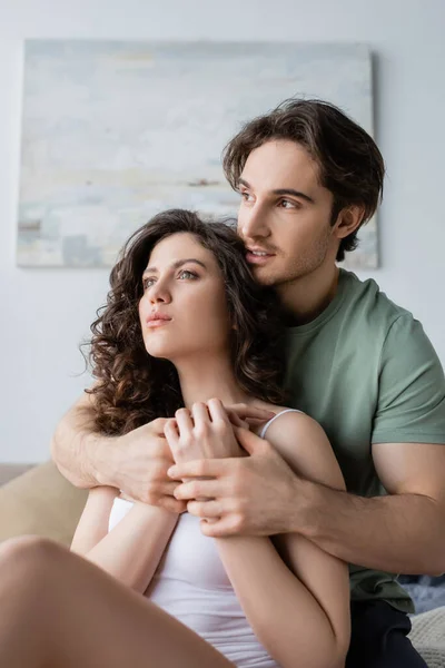 Homme en t-shirt vert étreignant femme sensuelle à la maison — Photo de stock