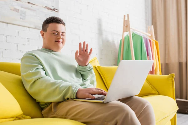 Teenager with down syndrome having video call on laptop on couch at home — Stock Photo